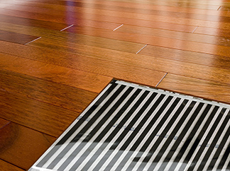 A heated hardwood floor with cutaway, showing the thin FilmHeat heating element.
