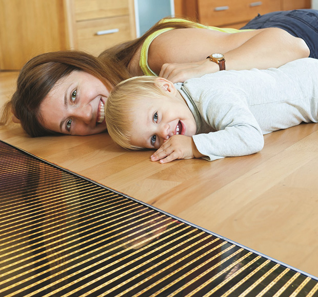A woman and her child on a warm floor, showing the FilmHeat heating element.