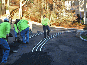 Heated driveway being installed in asphalt (with heated tire tracks).